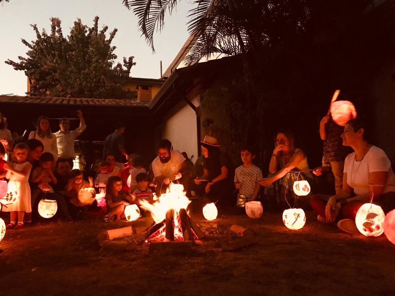 Pais e Crianças, em volta de uma fogueira com lanternas comemorando