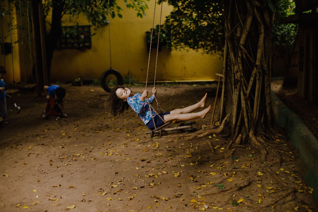 Criança brincando no balanço e sorrindo para a foto