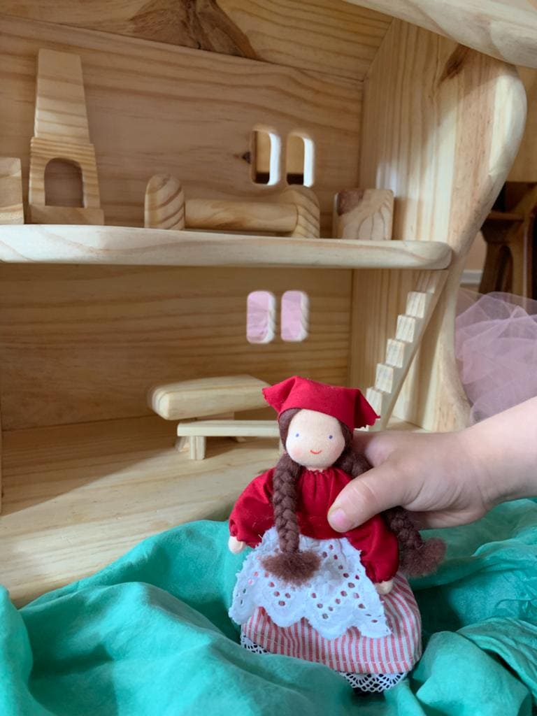 Criança brincando com uma boneca e uma casa de boneca